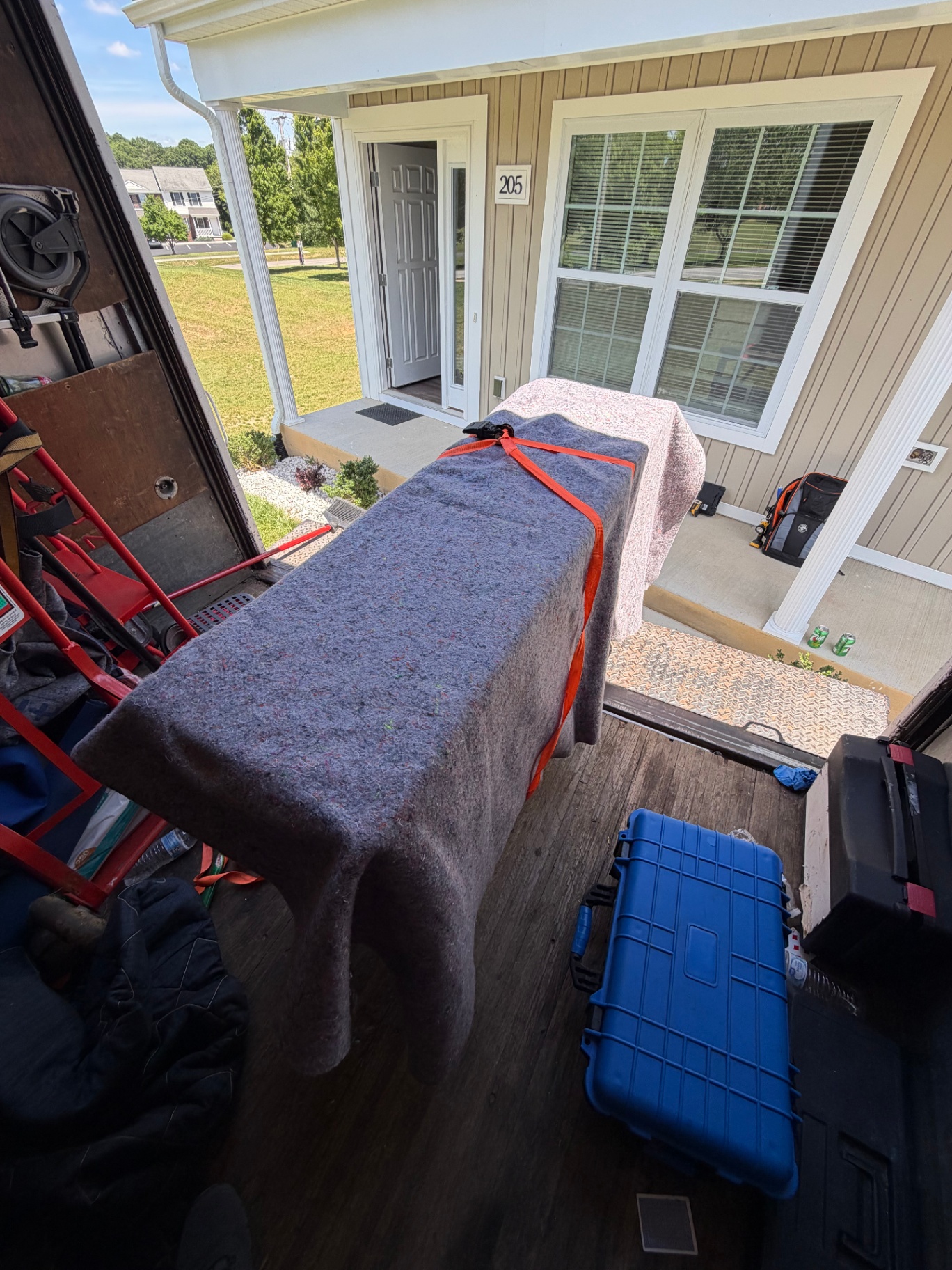 Furniture wrapped in moving blankets and strapped, staged on a customer's porch